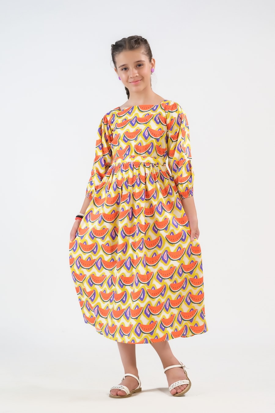 Girl wearing the yellow Watermelon Whirl long dress with orange watermelon motifs and three-quarter sleeves.